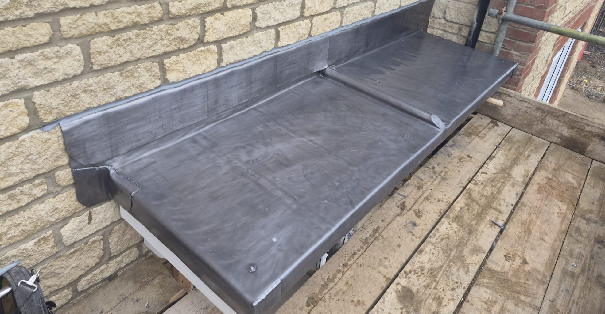 Hand-formed lead trays and flashing dressed against a brick wall